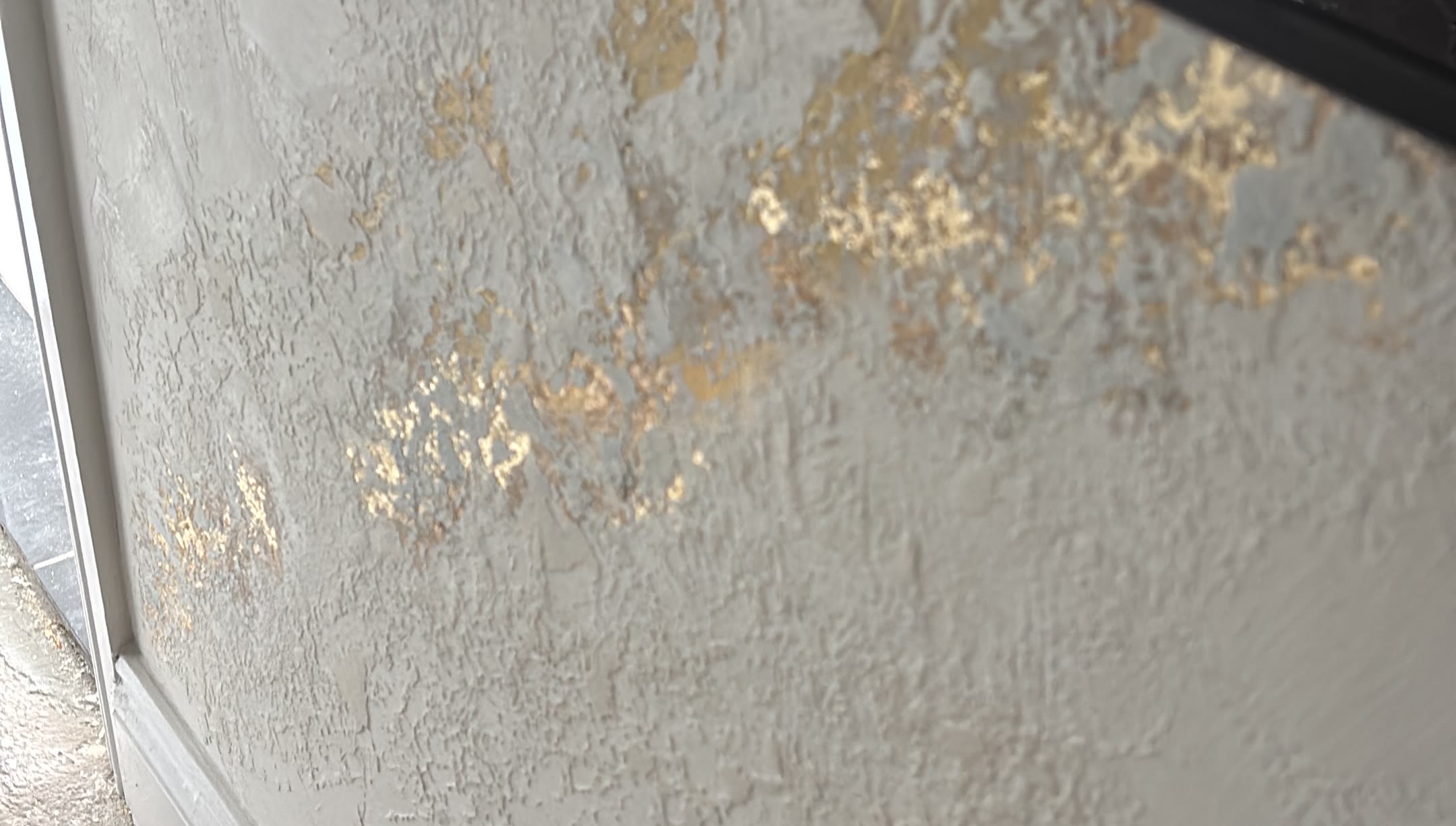Close up of gold leaf pressed into white marmorino plaster