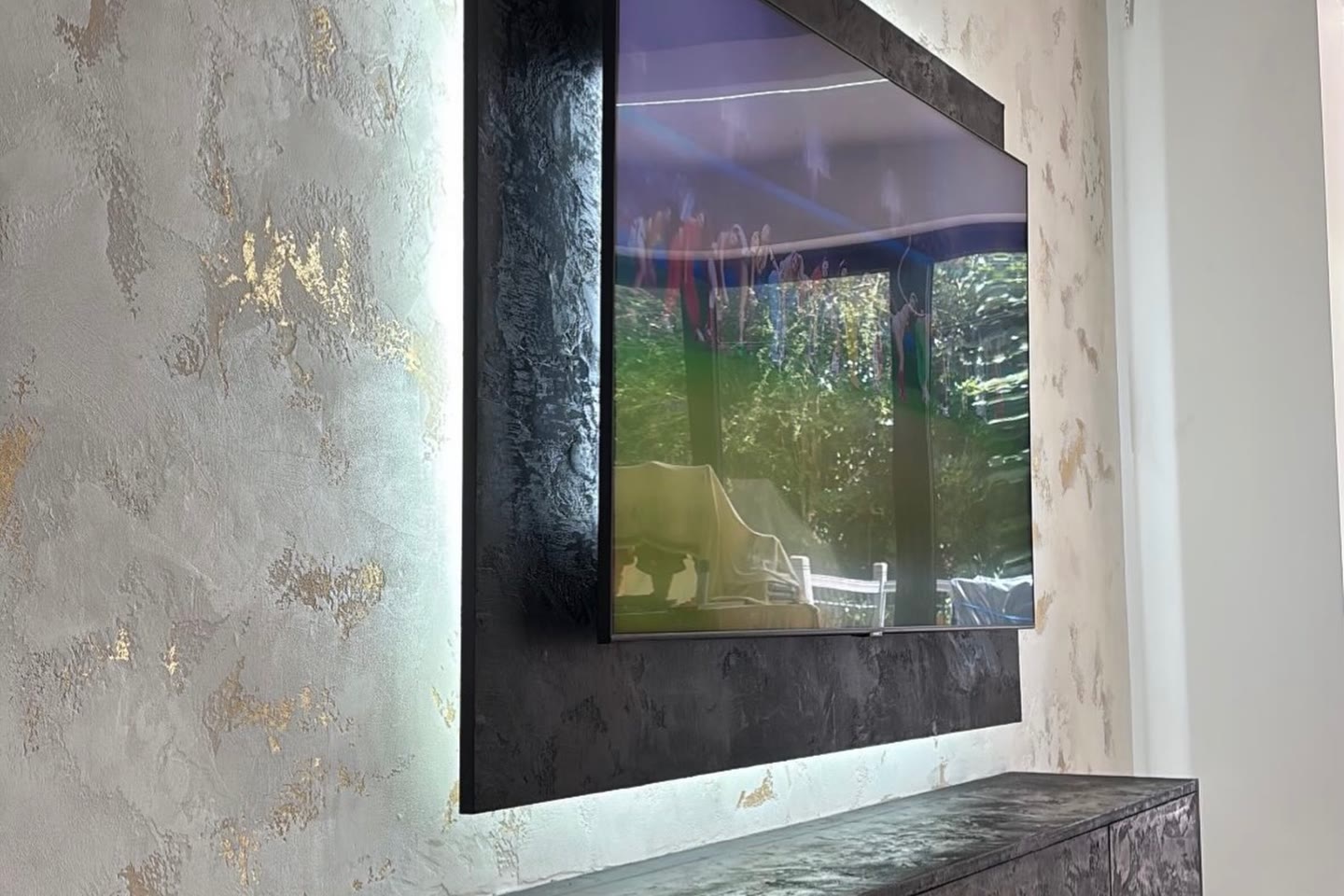 White marmorino media wall with gold detail and black polished cabinets